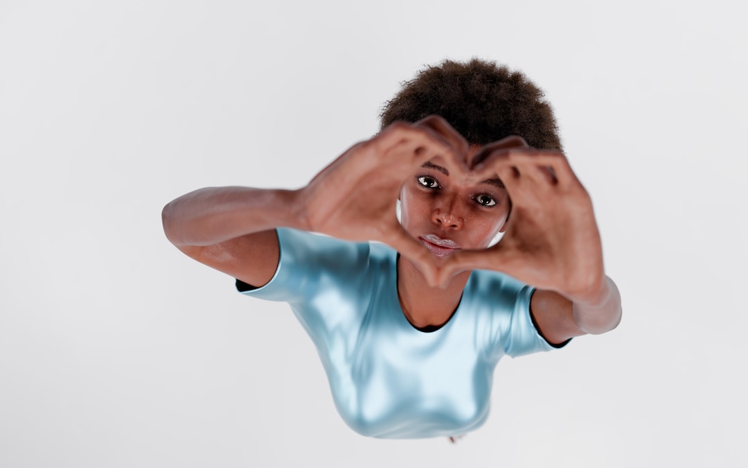 Young person forms heart shape with hands.