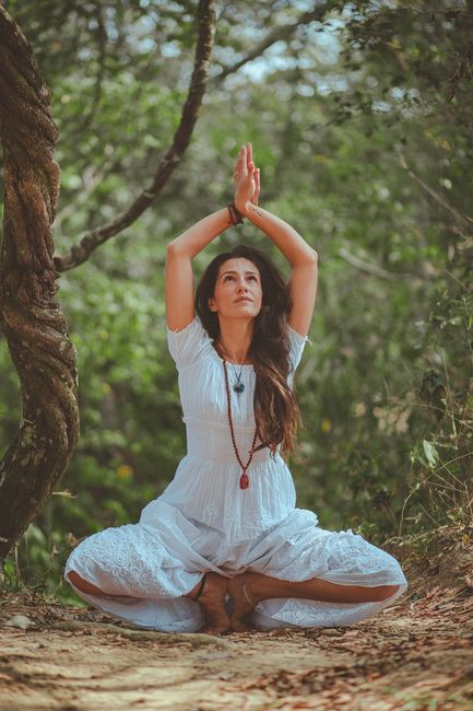 Woman in yoga pose on a mountain overlooking a serene landscape