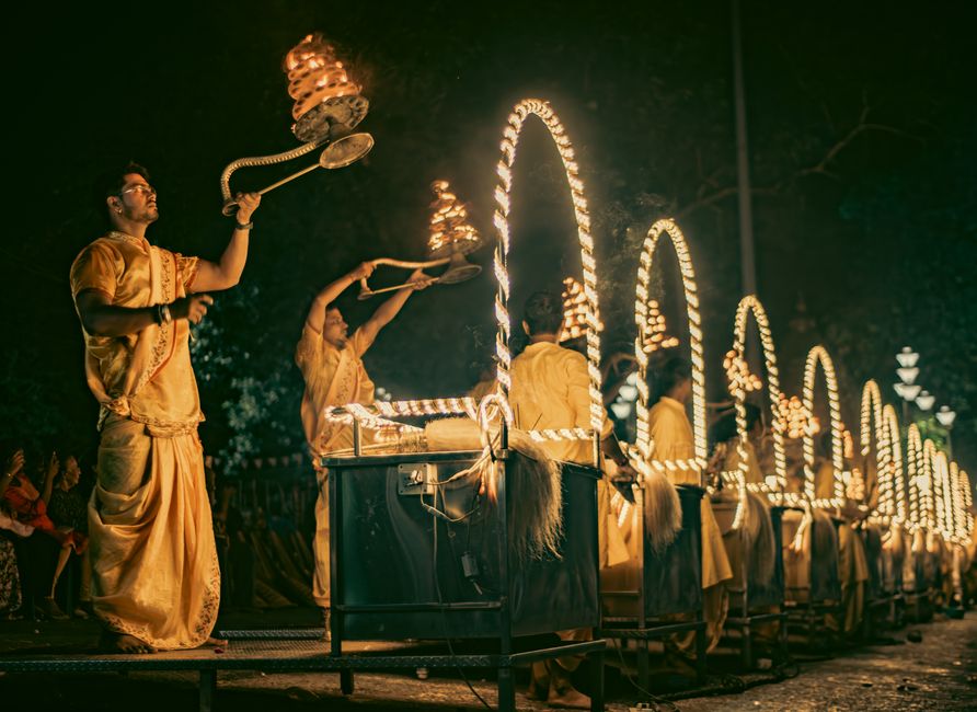 Woman meditating with hands in prayer position amidst candles and flowers