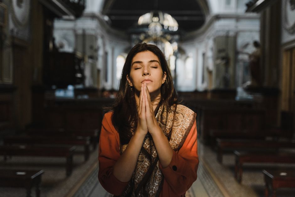 Person meditating with hands in prayer position outdoors