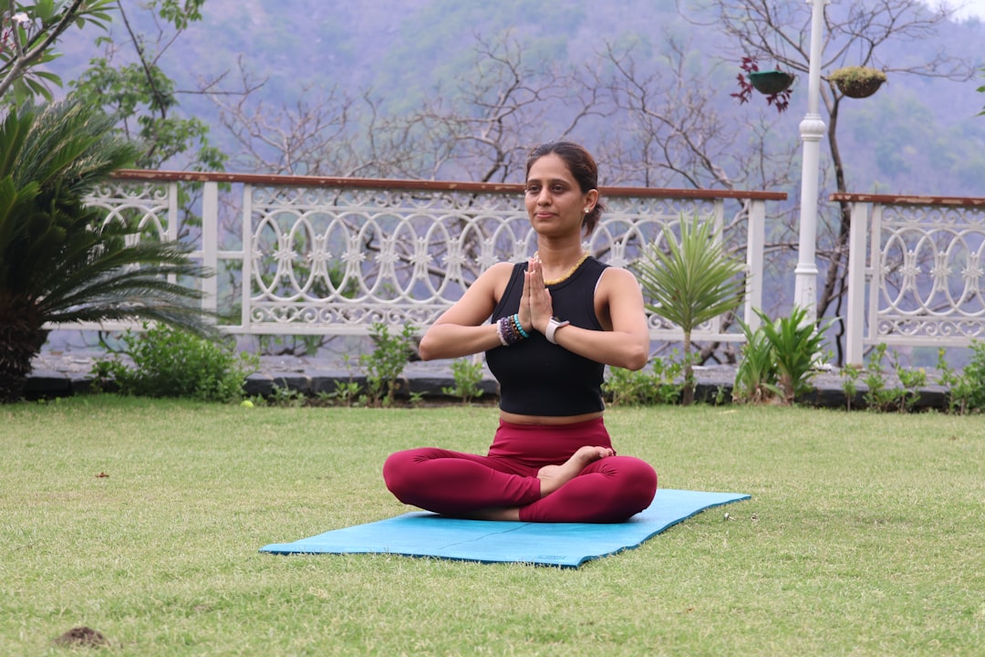 Woman meditating on a yoga mat outdoors.