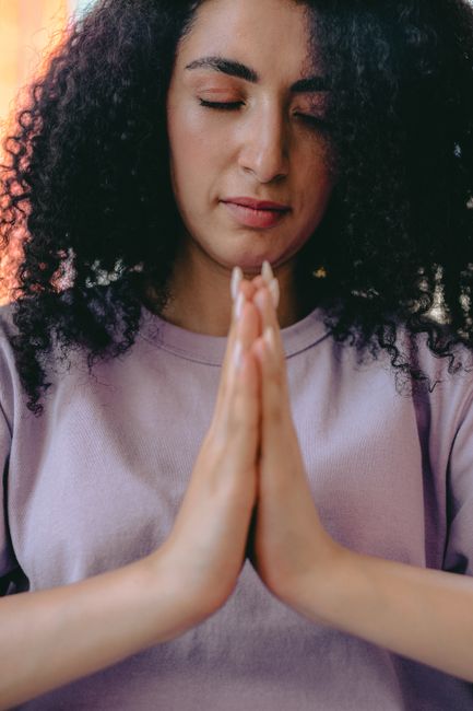 Person meditating in nature with hands together